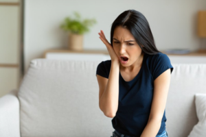 Woman holding her jaw in shock because she chipped a tooth