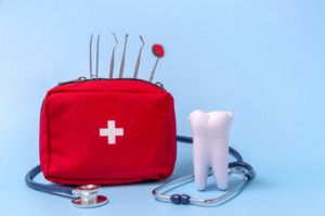 Red emergency kit on blue background stuffed with dental supplies