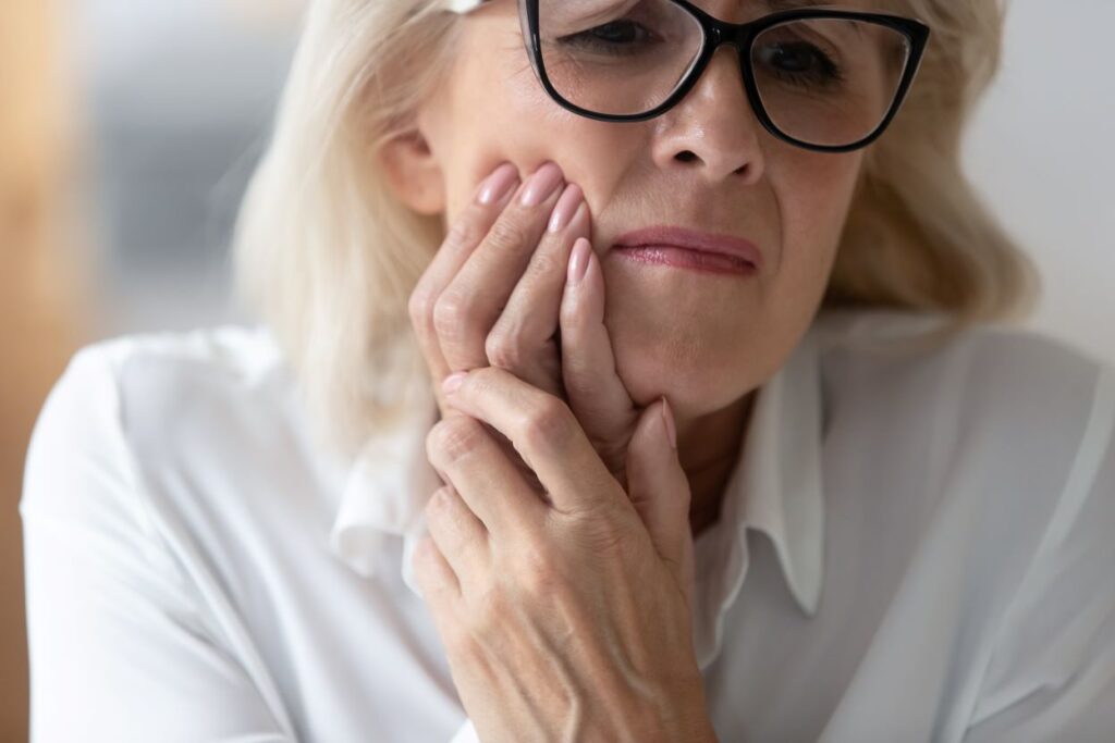 A woman clutching her jaw in pain.