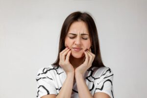 Grimacing woman struggling with facial pain